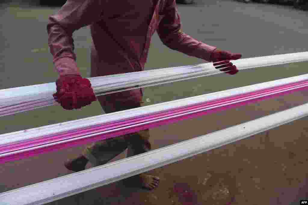 A man coats strings for flying kites with colored glass powder ahead of &#39;Uttarayan&#39; or Kite festival, in Ahmedabad, India.