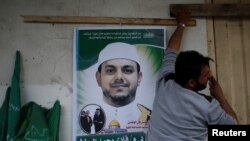 Seorang pria menggantung poster foto insinyur listrik Palestina Fadi al-Batash, yang ditembak mati di Malaysia, di rumah keluarganya di Jalur Gaza utara, 21 April 2018. (Foto: dok).