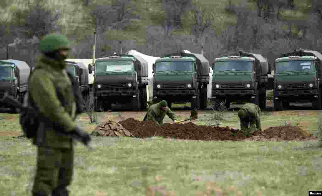 Armed men, believed to be Russians, dig trenches near the Ukrainian military base in Perevalnoye outside Simferopol, March 17, 2014. 