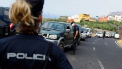 A police officer stands guard as residents line up in their cars following the eruption of a volcano on the Canary Island of La Palma, in La Laguna, Spain, September 21, 2021.