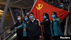 Medical workers from outside Wuhan pose for pictures with a Chinese Communist Party flag at the Wuhan Railway Station before leaving the epicentre of the novel coronavirus disease (COVID-19) outbreak, in Hubei province, China March 17, 2020. Picture taken