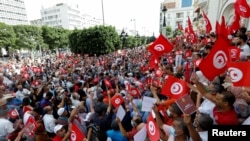 Demonstrators carry flags and banners during a protest against the Tunisian President Kais Saied's seizure of governing powers, in Tunis, Tunisia, Sept. 26, 2021.