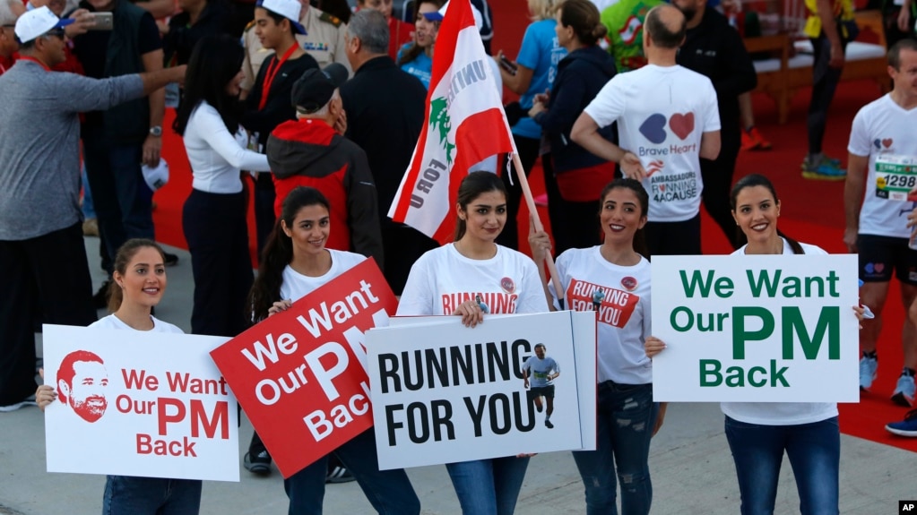 Lebanese women hold placards supporting the outgoing Lebanese Prime Minister Saad Hariri to return from Saudi Arabia during the Beirut Marathon in Beirut, Lebanon, Nov. 12, 2017. 