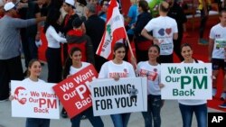 Lebanese women hold placards supporting the outgoing Lebanese Prime Minister Saad Hariri to return from Saudi Arabia during the Beirut Marathon in Beirut, Lebanon, Nov. 12, 2017. 