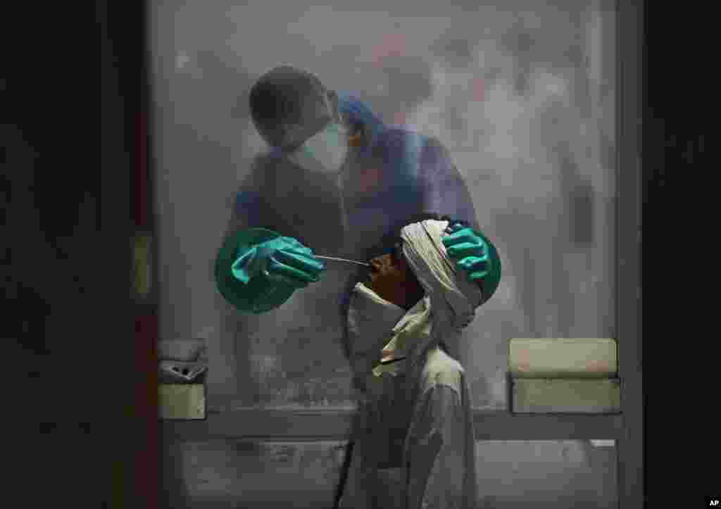 အိန္ဒိယနိုင်ငံ New Delhi မြို့မှာ swab နမူနာယူနေတဲ့ ကျန်မာရေးဝန်ထမ်းတဦး။ (ဇူလိုင် ၀၆၊ ၂၀၂၀)