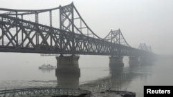 FILE - Trucks move across the bridge linking North Korea with the Chinese border city of Dandong, March 3, 2016. 