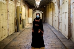 Israeli Arab Rana Hijazi,19, poses for a portrait wearing her protective face mask in the alleys of Jerusalem's old city, Tuesday, July 21, 2020. Hijazi says "she advice all people to wear face masks because it is very important for their health.