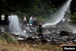 FILE - A firefighter works in the wreckage of a Boeing 737 plane that crashed in the agricultural area of Boyeros, south of Havana, shortly after taking off from Havana's main airport in Cuba, May 18, 2018.