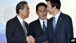 Japanese Foreign Minister Fumio Kishida, center, watches as Chinese Foreign Minister Wang Yi, left, shakes hands with South Korean Foreign Minister Yun Byung-se after the press conference following the trilateral meeting in Tokyo, Aug. 24, 2016.
