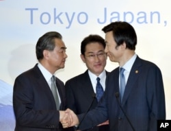 FILE - Japanese Foreign Minister Fumio Kishida, center, watches as Chinese Foreign Minister Wang Yi, left, shakes hands with South Korean Foreign Minister Yun Byung-se after the press conference following the trilateral meeting in Tokyo, Aug. 24, 2016.