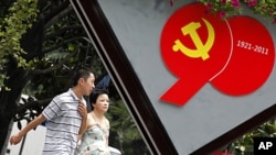A couple walks past an advertisement to celebrate the upcoming 90th anniversary of the founding of the Communist Party of China on July 1, in Shanghai, China, June 22, 2011.