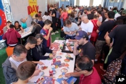 FILE - Collectors exchange World Cup stickers for their albums at a trading event outside the Pacaembu stadium in Sao Paulo, Brazil, May 26, 2018.