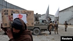 FILE - An Afghan man carries a package distributed by a Turkish humanitarian aid group at a distribution center in Kabul, Afghanistan, Dec. 15, 2021. 