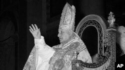 FILE - Pope John XXIII blesses spectators as he is carried on a portable throne to St. Paul's Basilica in Rome, Jan. 25, 1959.