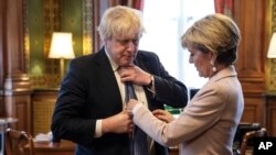 Dasi Menlu Inggris Boris Johnson dirapikan oleh rekannya dari Australia, Menlu Julie Bishop, di kantornya di Foreign and Commonwealth Office di London, hari Kamis, 23 Februari 2017 (foto: Jack Taylor/Pool Photo via AP)