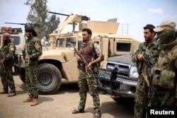 FILE - Fighters of the Syrian Democratic Forces stand guard in Deir el-Zour, Syria, May 1, 2018.