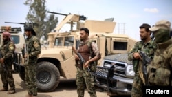 FILE - Fighters of Syrian Democratic Forces (SDF) stand guard in Deir al-Zor, Syria, May 1, 2018.