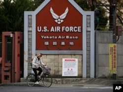 FILE - A woman cycles from the U.S. Air Force's Yokota Air Base in Tokyo's western suburbs, April 27, 2017. Residents living near U.S. military bases in Japan are on the frontline of North Korea’s dispute with America, and if Pyongyang were to attack they would have just minutes to shelter from incoming missiles.