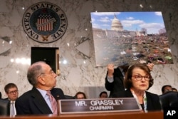 Senate Judiciary Committee Chair Sen. Chuck Grassley, R-Iowa, left, looks at a poster of 7,000 pairs of shoes that were displayed outside the Capitol Tuesday to represent victims of gun violence since the shootings at Sandy Hook Elementary School, as Ranking Member Sen. Dianne Feinstein, D-Calif., right, speaks during a committee hearing on the Parkland, Florida, school shootings and school safety, March 14, 2018, on Capitol Hill in Washington.