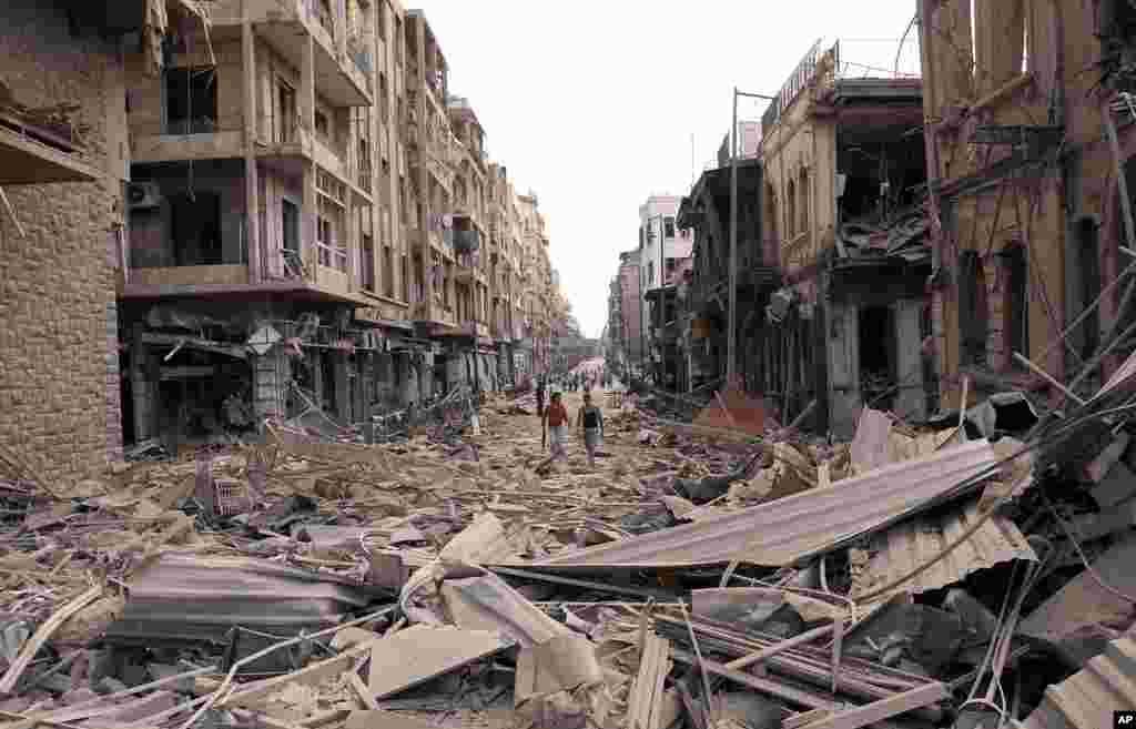 This photo released by the Syrian official news agency SANA shows Syrian men walking between destroyed buildings where bombs exploded in Saadallah al-Jabri square, in Aleppo, Syria, October 3, 2012.