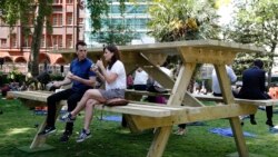 People sit at an oversize picnic table in Soho Square in London May 19, 2014.