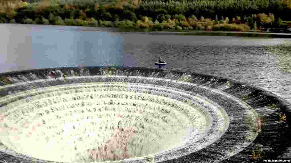 A fisherman floats in a boat close to a &#39;plughole&#39; on a reservoir in Derbyshire, Britain, in this still image taken from video obtained from social media.