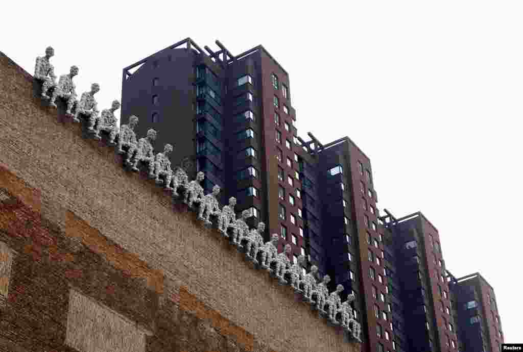 A row of statues are seen on the top of a building next to apartment blocks in Beijing, China.