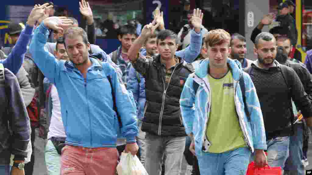 Des réfugiés saluent de la main&nbsp;à leur arrivée&nbsp;à la gare principale de Munich, en Allemagne, 5 septembre 2015.