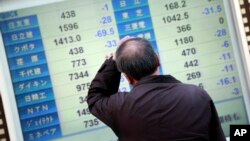 A man scratches his head as he looks at an electronic stock board showing Japan's Nikkei 225 in Yokohama, near Tokyo.