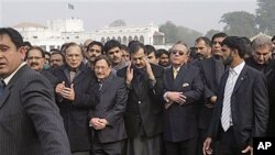 Pakistani Prime Minister Yousuf Raza Gilani, center, surrounded by officials and members of his government, offers a prayer during the funeral procession of Punjab Gov. Salman Taseer in Lahore, Pakistan, Jan 5, 2011