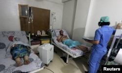 FILE - Civilians breathe through an oxygen mask at al-Quds hospital, after a hospital and a civil defence group said a gas, what they believed to be chlorine, was dropped alongside barrel bombs on a neighbourhood of the Syrian city of Aleppo, Syria, early August.