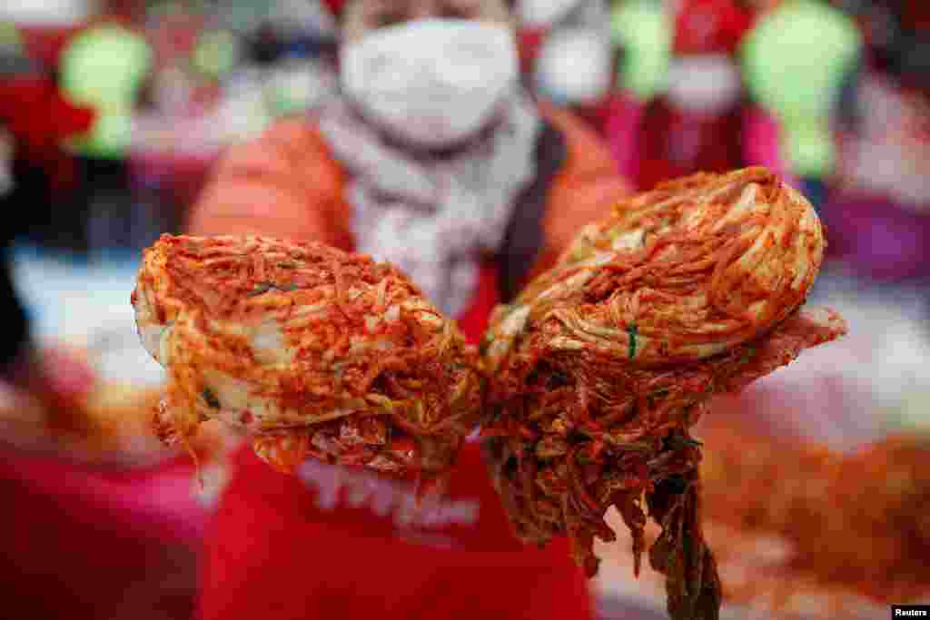 A woman poses for photographs with the traditional side dish &#39;Kimchi&#39; during the Seoul Kimchi Festival in central Seoul, South Korea.