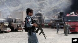 Un agente de policía de Afganistán custodia el área tras el ataque que dejó camiones de la OTAN incendiados en la base Torkham.