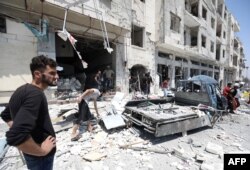 FILE - Syrians gather at a site of car bomb in the northwestern Syrian city of Idlib, Aug. 2, 2018.