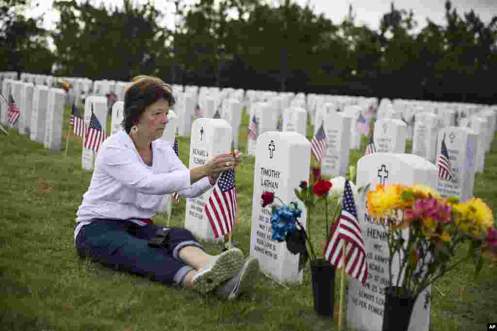 Vickie Hunt senta-se à frente do túmulo de seu marido falecido, veterano do Vietname Cpl. Timothy Hunt, na Cemitério Nacional de Geórgia no Dia da Memória aos Veteranos, Geórgia, EUA &nbsp;