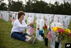 Vickie Hunt sits next to the grave of her late husband, Vietnam veteran Cpl. Timothy Hunt, at Georgia National Cemetery on Memorial Day, Monday, May 25, 2015, in Canton, Ga.