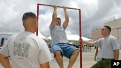 FILE - Matt Elam, center, competes in a US Marine pull-up contest while Marine recruiters Sgt. Marco Hartanto, left, and Gysgt. Brian Lancioni watch during BayFest 2006 held at Marine Corps Base Hawaii, Tuesday, July 4, 2006, in Kaneohe, Hawaii.