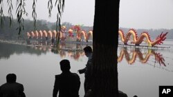 Chinese security guards rest near a giant dragon shaped lantern set up to mark mid-autumn festival in Beijing, China, September 12, 2011.