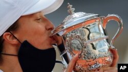 Poland's Iga Swiatek kisses the trophy after winning the French Open tennis tournament against Sofia Kenin of the US in two sets 6-4, 6-1, at the Roland Garros stadium in Paris, France, Oct. 10, 2020. 