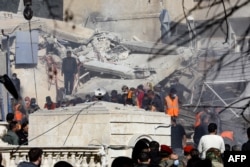 Rescuers gather in front of a building destroyed in a reported Israeli strike in Damascus, Syria, on Jan. 20, 2024.