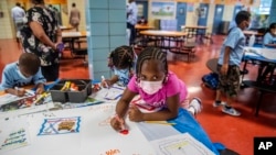 FILE — In this Aug. 17, 2021 file photo, students write and draw positive affirmations on poster board at P.S. 5 Port Morris, an elementary school in The Bronx borough of New York. New York City will phase out its program for gifted and talented students 