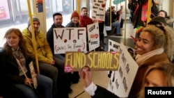 Striking teachers sit on a tube train at Hammersmith to travel to a protest march in London, England Feb. 1, 2023.