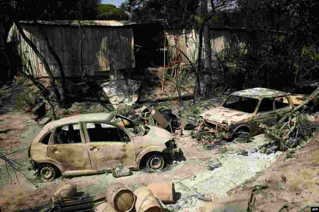 Burned out cars sit outside a house, destroyed by forest fires near Grimaud, in the department of Var, southern France.
