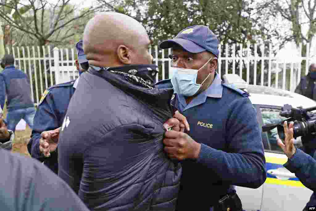 A South African police member grabs a protester during their picket against the government of Zimbabwe&#39;s alleged state corruption, media freedom and deteriorating economy outside the Zimbabwean Embassy in Pretoria.
