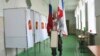 A polling station official with Russian national and Crimea flags is prepared for the 2018 Russian presidential election, in Simferopol, Crimea, March 17, 2018.