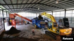 A security officer stands as a heavy vehicle loads the trash into a machine that produces Refuse Derived Fuel at the Bantar Gebang landfill in Bekasi, West Java province, Indonesia, Aug. 12, 2021.