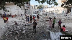 Niños palestinos observan el lugar de un ataque israelí contra una casa, en medio del conflicto entre Israel y Hamás, en el campo de refugiados de Maghazi, en el centro de la Franja de Gaza, el 14 de agosto de 2024.