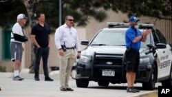 School police officers look on as students leave Columbine High School, April 16, 2019, in Littleton, Colo. Following a lockdown at Columbine and other Denver area schools, authorities say they are looking for a woman suspected of making threats.