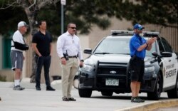 School police officers watch students leave Columbine High School, April 16, 2019, in Littleton, Colo. Authorities were looking for a woman suspected of making threats.