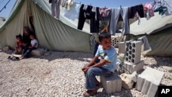 A Syrian refugee boy sits outside his family's tent at a temporary camp in the Lebanese town of Marj near the border with Syria, May 20, 2013. 